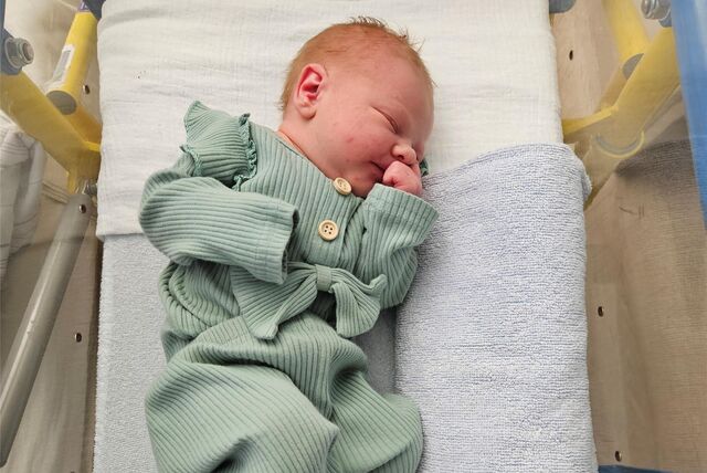 Emily ist ein Neujahrsbaby und liegt im hellgrünen Pyjama in einem Kinderbett.
