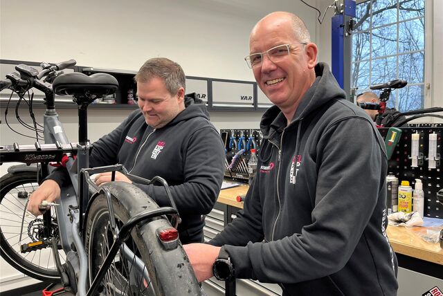 Zwei Fahrradmonteure arbeiten an einem Rad.