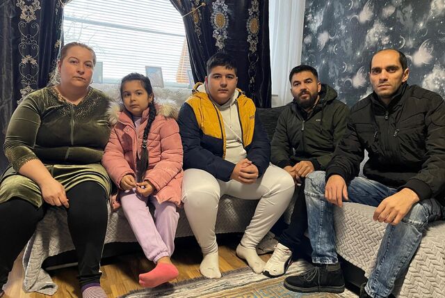 Familie Mudev sitzt auf dem Sofa in ihrem Wohnzimmer.