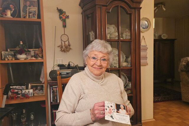 Edith Gayk, eine ältere Frau, sitzt in ihrem Wohnzimmer und hält eine Geburtstagskarte in der Hand.