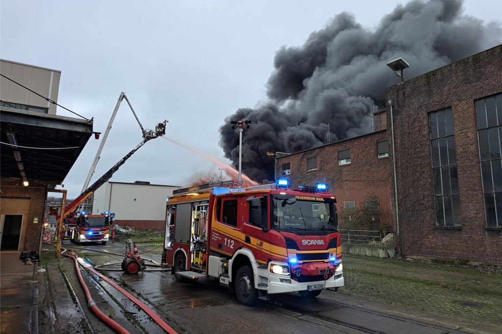 Ein Feuerwehrwagen steht vor einem Gebäude auf dem Gelände der ehemaligen Zeche Auguste Victoria (AV) in Marl, über dem eine große dunkle Rauchwolke zu sehen ist. Ein Feuerwehrwagen steht vor einem Gebäude auf dem Gelände der ehemaligen Zeche Auguste Victoria (AV) in Marl, über dem eine große dunkle Rauchwolke zu sehen ist.