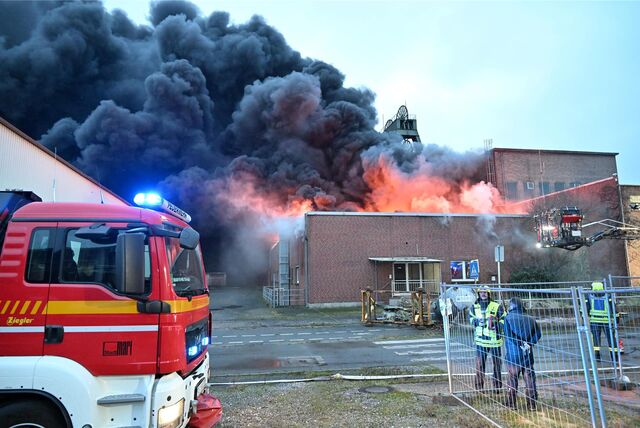 Ein Einsatzfahrzeug der Feuerwehr steht vor der brennenden Grubenwarte der ehemaligen Zeche Auguste Victoria (AV) in Marl.