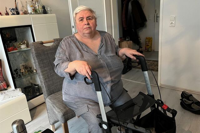 Tatiana Petrova sitzt in ihrem Wohnzimmer. Vor ihr steht ihr Rollator.