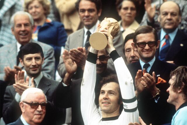 Kapitän Franz Beckenbauer (M.) hebt an der Seite von Torhüter Sepp Maier (r.) und dem englischen FIFA-Präsidenten Stanley Rous (ll) im Olympiastadion nach dem Endspiel der Fußball-WM den eroberten WM-Pokal hoch.