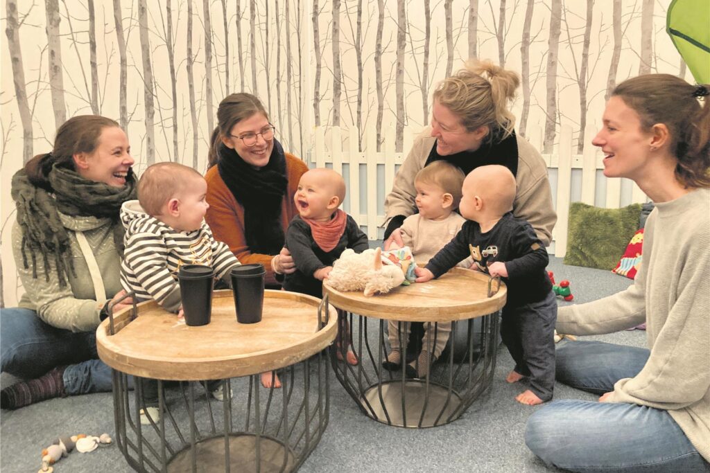Vier Mütter und vier kleine Kinder in der Krabbelecke des Familiencafés. Vier Mütter und vier kleine Kinder in der Krabbelecke des Familiencafés.