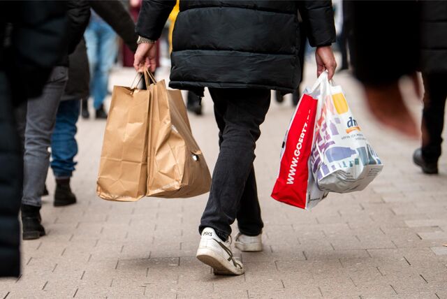 Eine Person trägt mehrere Einkaufstaschen in den Händen und geht durch eine Einkaufsstraße in Essen.