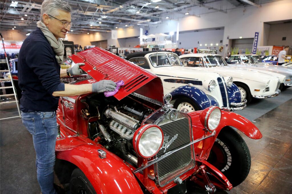 Ein Mann zeigt den Motorraum eines Oldtimers auf der Techno Classica in Essen. Ein Mann zeigt den Motorraum eines Oldtimers auf der Techno Classica in Essen.