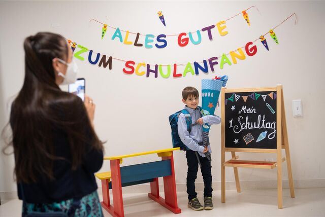 Ein Kind mit Schultüte steht vor einer kleinen Tafel mit der Aufschrift „Mein 1. Schultag“.