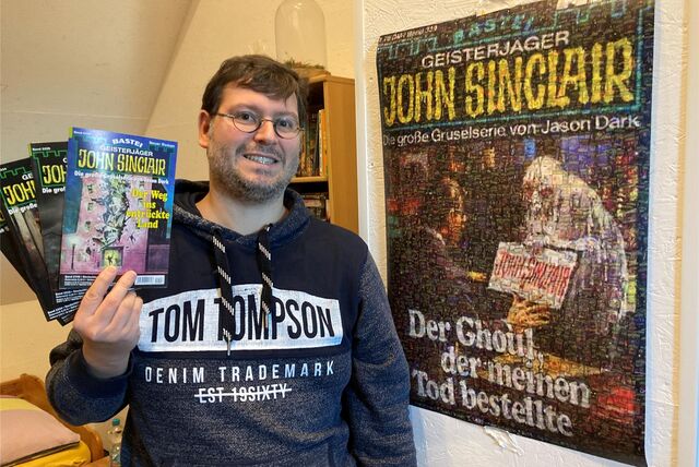Geisterjäger-Autor Oliver Müller steht neben dem Plakat des John-Sinclair-Romans „Der Ghoul, der meinen Tod bestellte“. Inzwischen hat der 40-jährige Marler mehrere Romane dieser Serie verfasst.