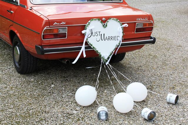 An einem roten Audi A6 hängt ein Schild mit der Aufschrift „Just Married“ und Ballons und Dosen wurden an dem Auto befestigt.