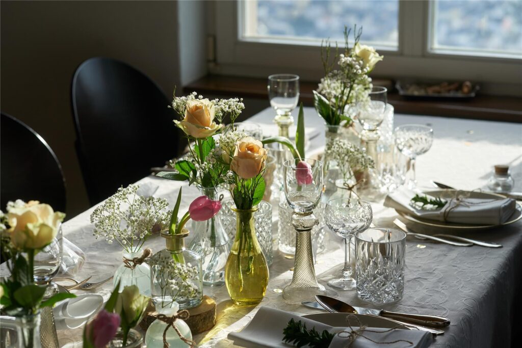 Ein Tisch ist mit Blumen und Vasen für eine Hochzeit eingedeckt. 