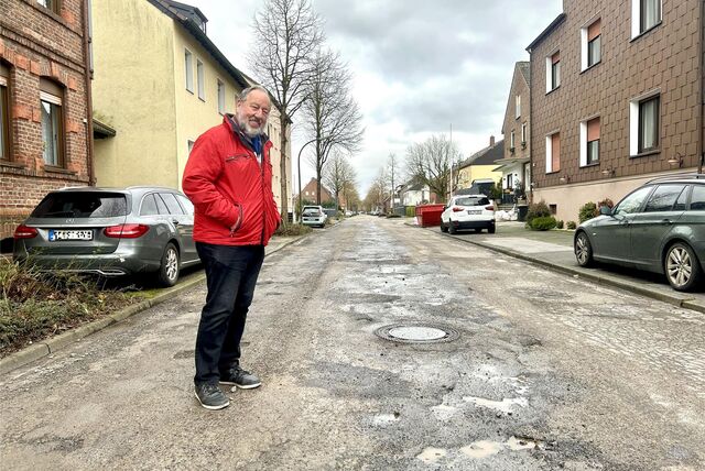 Dr. Robert Theißen steht neben Schlaglöchern auf der Auguststraße.