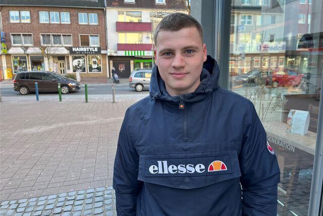 Ein junger Mann steht in einer Innenstadt.