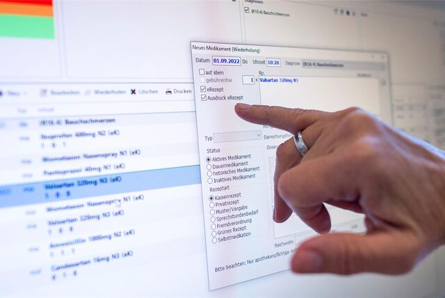 Ein Hand zeigt in einer Arztpraxis auf den Monitor, an dem gerade ein E-Rezept ausgestellt wird.