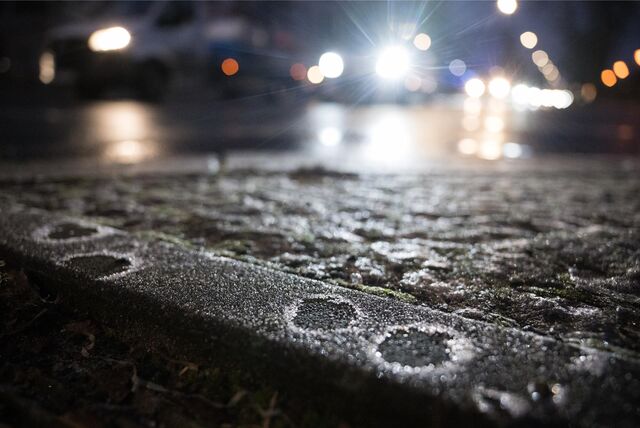 Eiskristalle haben sich auf dem Randstein an einer Straße gebildet. Nach Tagen mit Minusgraden kommt es nun zu glatten Straßen und Gehwegen.