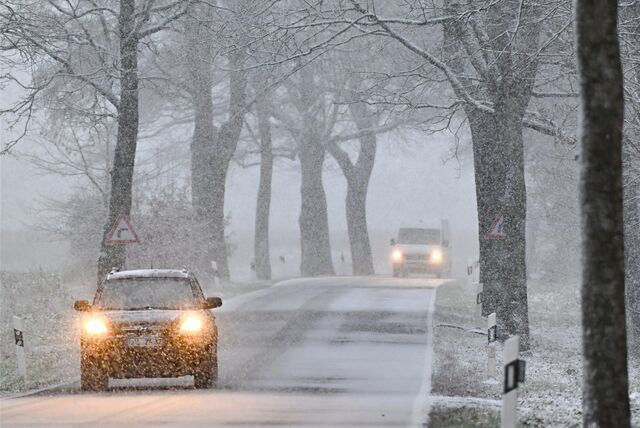 Zwei Autos fahren über eine beschneite Landstraße.