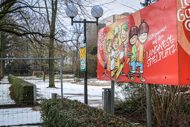Drei Kinder spielen auf einer Rutsche auf einem Spielplatz.