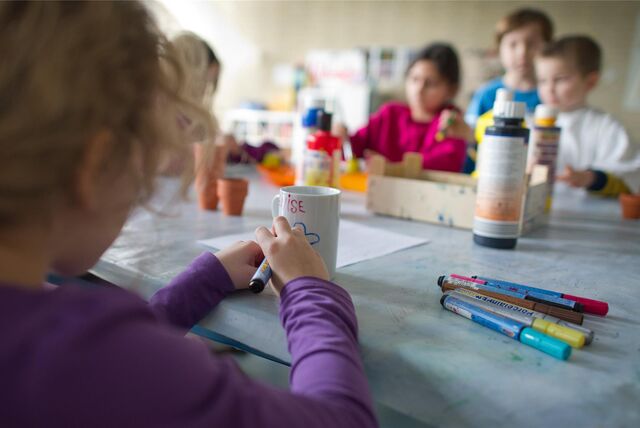 Kinder bemalen eine Tasse.
