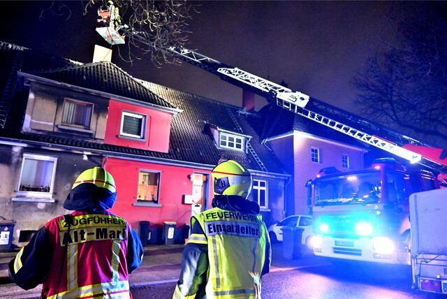 Zwei Feuerwehrleute beobachten, wie ein Kollege auf einer Drehleiter steht.