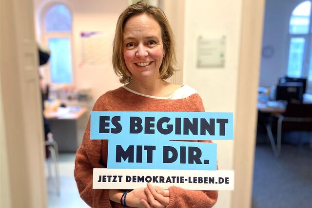 Daniela Franken-Vahrenholt hält ein Schild mit der Aufschrift „Es beginnt mit Dir“ in die Kamera.