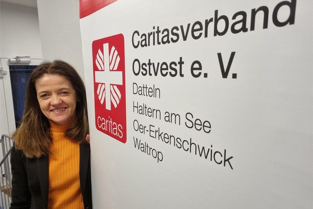Eine Frau steht an einem Werbeaufsteller der Caritas.