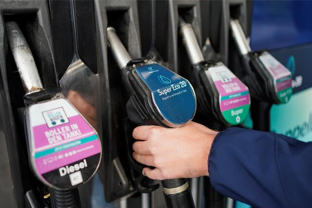 Eine Hand greift nach einem Zapfhahn an einer Tankstelle.