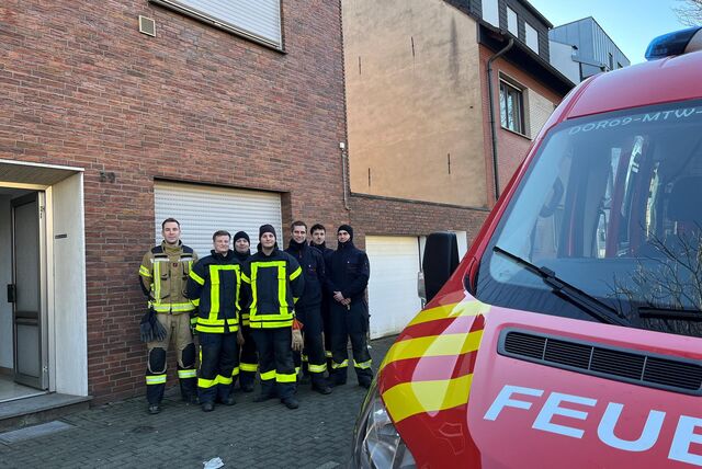 Feuerwehrleute mit Fahrzeug vor einem leerstehenden Haus