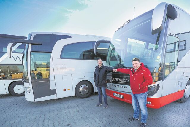 Zwei Männer stehen vor einer Bus-Reihe.