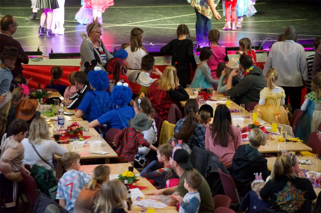 Kinder und Eltern an Tischen beim Kinderkarneval in der Aula des Adalbert-Stifter-Gymnasiums in Castrop. Kinder und Eltern an Tischen beim Kinderkarneval in der Aula des Adalbert-Stifter-Gymnasiums in Castrop.