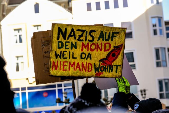 Ein Plakat wird bei einer Demonstration in die Höhe gehalten.