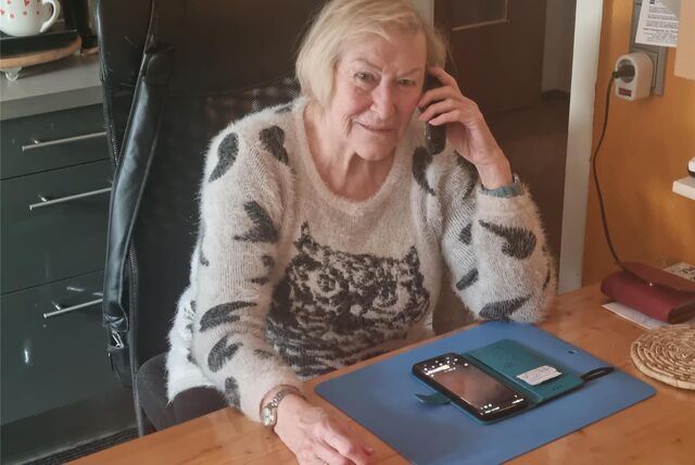 Eine Frau sitzt mit Festnetztelefon am Ohr und Handy auf dem Tisch in einer Küche in Recklinghausen.