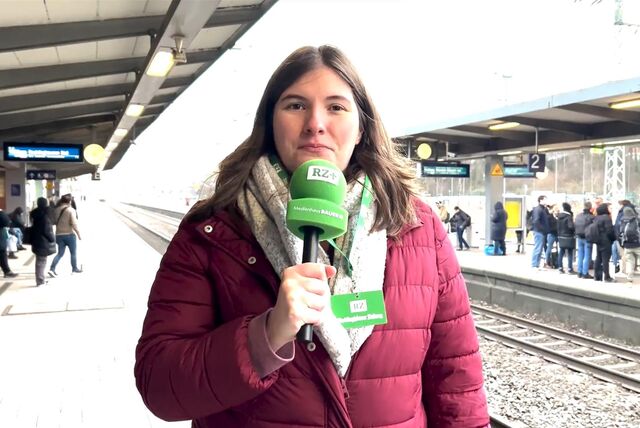 RZ-Reporterin Pauline Korte steht mit dem Mikrofon am Gleis im Bahnhof Recklinghausen. Im Hintergrund sind die Schienen und Reisende erkennbar.