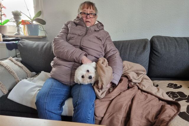 Eine Frau sitzt mit ihrem Hund auf der Couch.