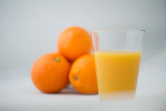 Orangen liegen neben einem Glas Orangensaft.