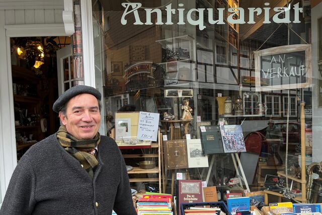 Ein Mann steht vor seinem Antiquariat.