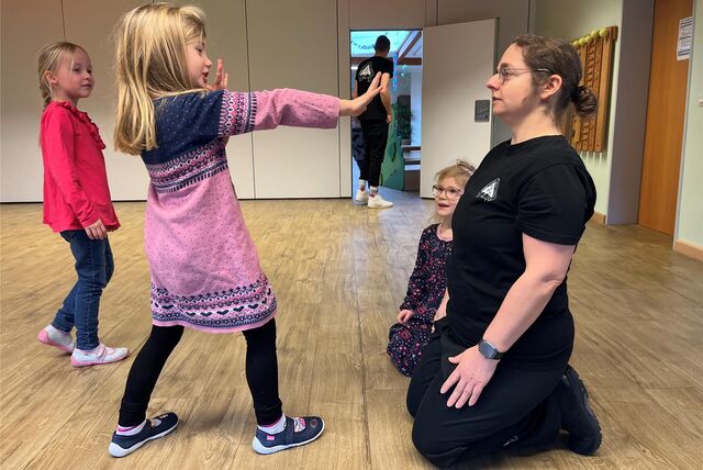 Kindergarten-Kind Ida stellt eine Karate-Übung vor und streckt ihre Arme aus.