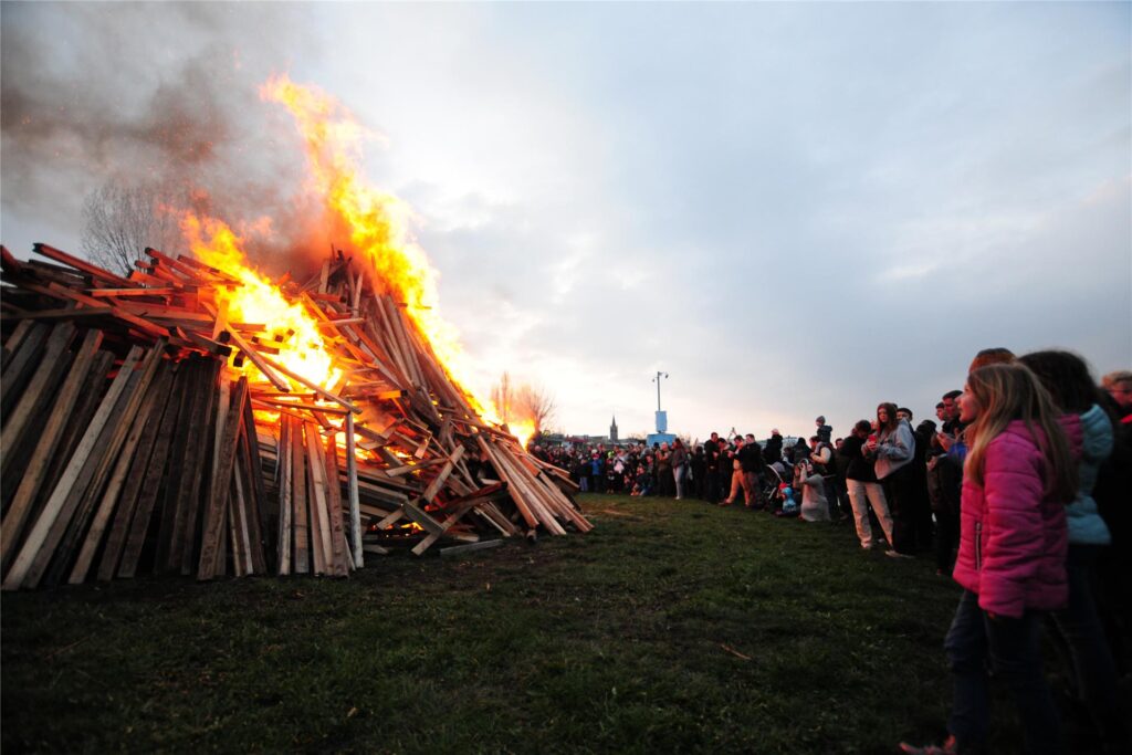 Menschen schauen sich ein Osterfeuer an. Menschen schauen sich ein Osterfeuer an.