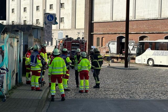 Es sind Einsatzkräfte von hinten zu erkennen. Ein Feuerwehrauto steht im Hintergrund.