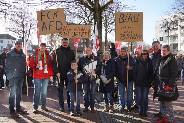 Menschen stehen nebeneinander auf einer Kundgebung.