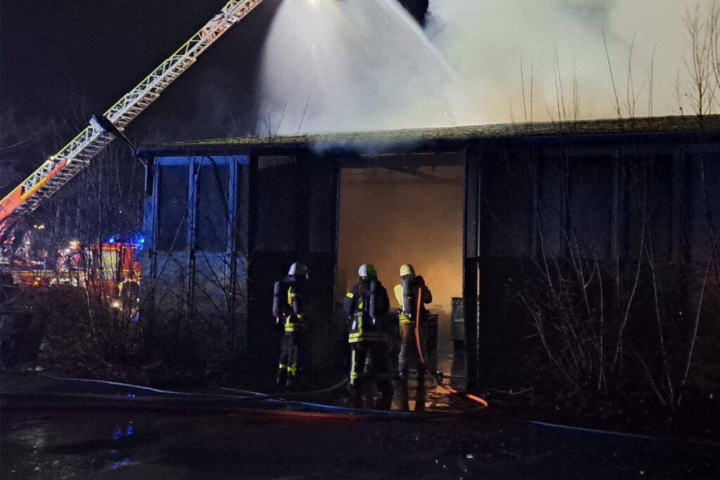 Feuerwehrleute unter Atemschutz löschen Flammen in einer alten Lagerhalle. Feuerwehrleute unter Atemschutz löschen Flammen in einer alten Lagerhalle.
