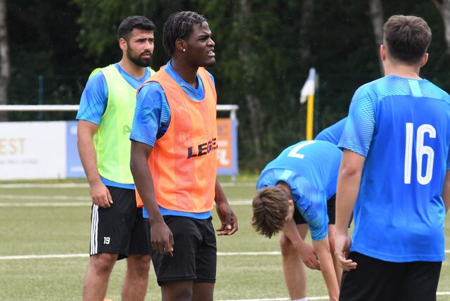 Fußballspieler Karl Heinz Manga (2.v.l.) trägt ein orangefarbenes Trainingsleibchen.