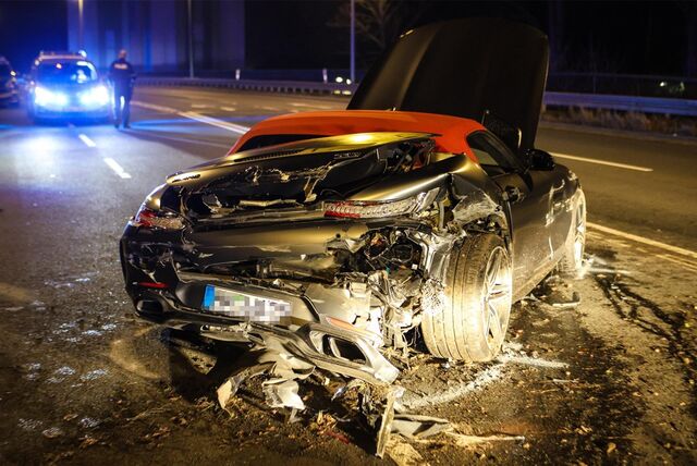 Ein kaputtes Auto nach einem Unfall. Im Hintergrund steht ein Polizeiauto.