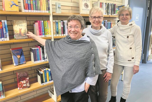 Drei Frauen vom Waltroper Büchereiteam vor der Regalwand.