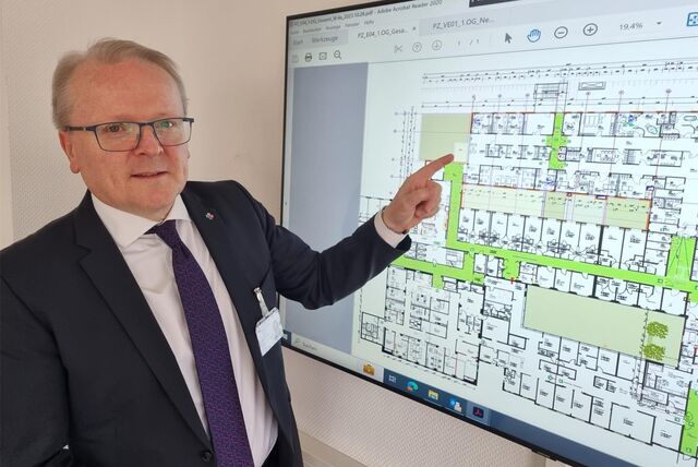 Wolfgang Müller, Geschäftsführer des St.-Vincenz-Krankenhauses in Datteln, zeigt auf einen Bildschirm, auf dem ein Bauplan des Perinatalzentrums zu sehen ist.