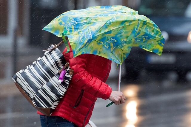 Eine Frau kämpft bei Sturm mit einem Regenschirm. (Symbolbild)