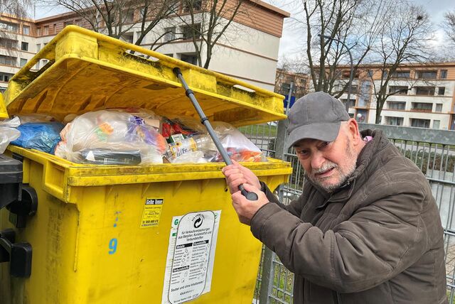 Lothar Schnabel drückt den Deckel einer Plastiktonne mit seinem Krückstock hoch.