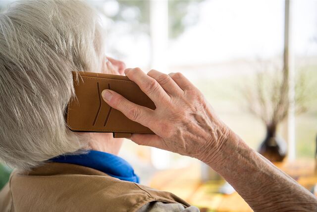 Eine Seniorin hält ein Telefon in der Hand