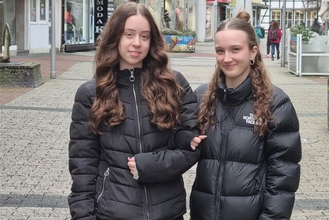 Zwei Mädchen stehen in einer Fußgängerzone.