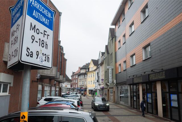Blick auf eine Einkaufsstraße, links sind Fahrzeuge geparkt.