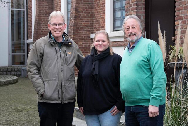 Drei Personen stehen vor einer Kirche